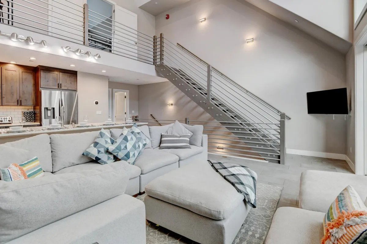 A cozy living area flows seamlessly into the kitchen, with sightlines to a dining space ideal for family feasts. The comfortable sofa and nearby kitchen area highlight the home’s open-concept design, perfect for both relaxing and entertaining.