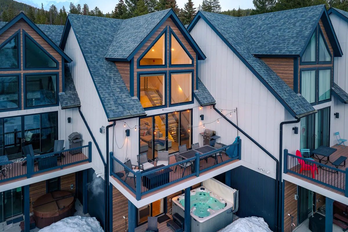 This image displays an exterior view of the private hot tub situated on the deck, framed by cozy balcony seating and large windows with wooden accents. The scene is set for relaxation, showcasing the hot tub as a focal point, with additional touches like seating and hints of mountain views, emphasizing both group gatherings and quiet moments.